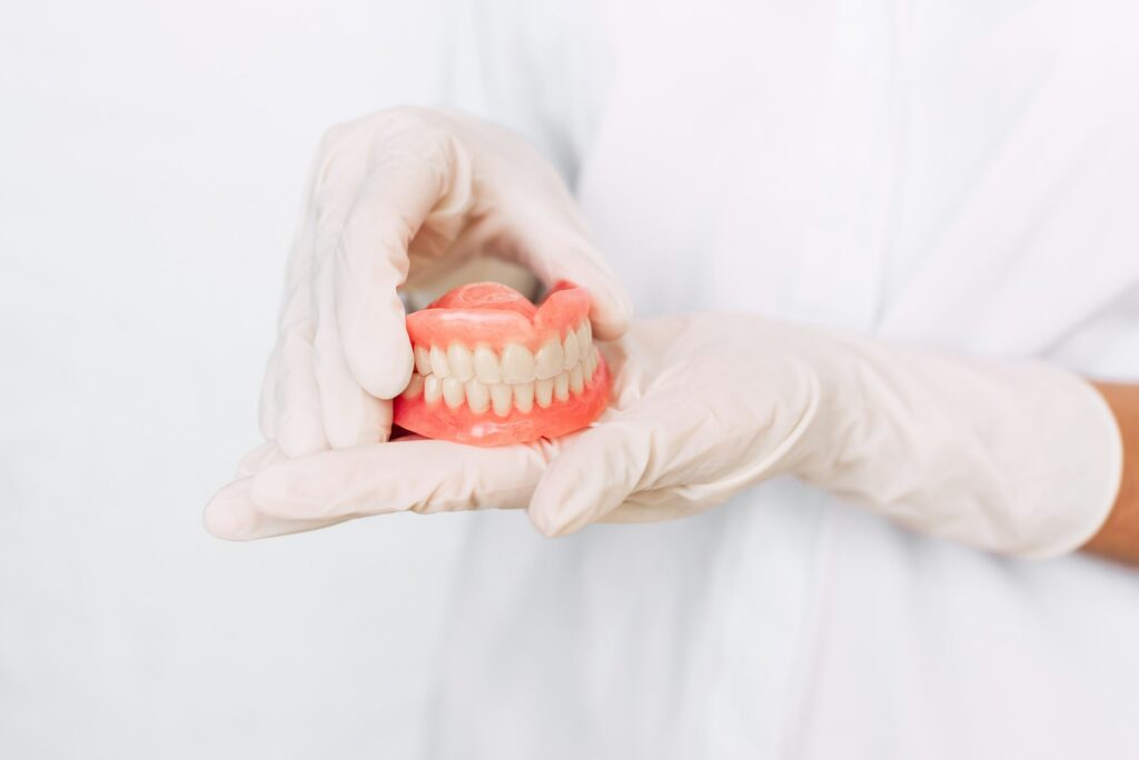 Dentist holding ceramic dental bridge. Front view of complete denture. Dentistry conceptual photo